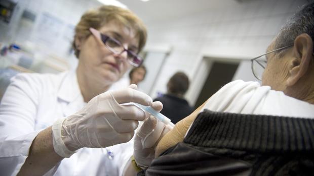 Una enfermera , vacunando a un paciente contra la gripe