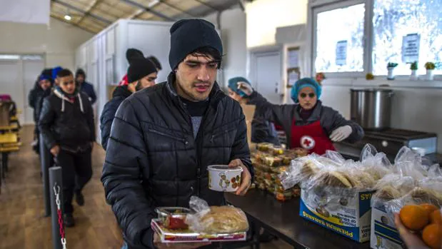 Varios refugiados reciben comida en un centro de tránsito para refugiados cerca de la frontera con Serbia en Tabanovce