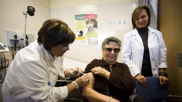 Médico vacunando contra la gripe a una paciente