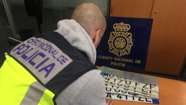 Un agente de la Policía nacional revisa varias matrículas falsas intervenidas en la operación