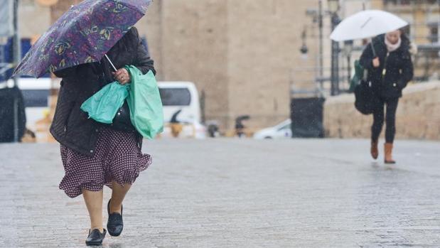 Transeúntes se protegen de la lluvia en Valencia, en una imagen de archivo