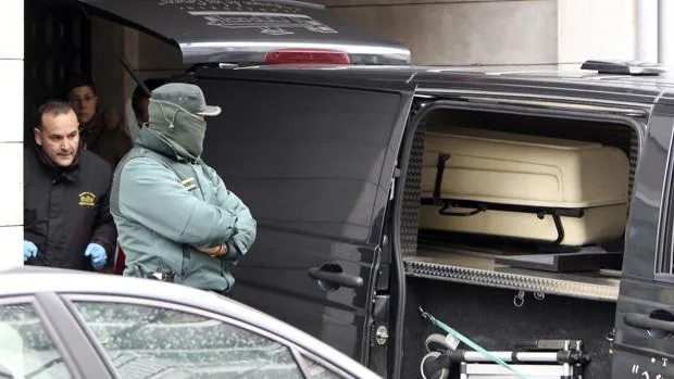 Un agente de la Guardia Civil permanece junto al furgón de los servicios funerarios