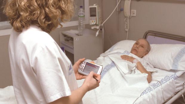 Una enfermera atiende a un pacientea los pies de su cama