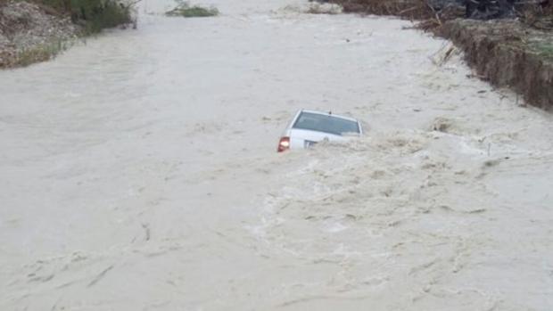 El vehículo arrastrado y casi hundido dentro del agua, en el río Serpis