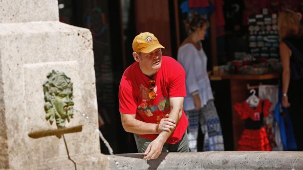 Un hombre se refresca en una fuente del centro de Valencia