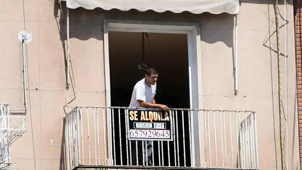 Imagen de un hombre con un cartel de un piso de alquiler