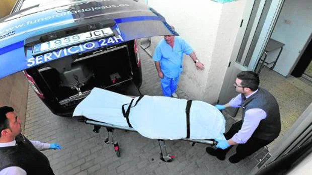 Empleados de la funeraria sacan del hospital una camilla con el cuerpo de Juan Carlos M.P