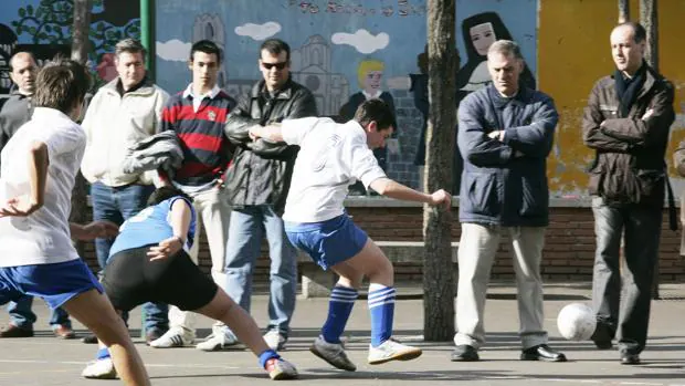 Un grupo de chavales, jugando al fútbol ante la mirada de varios espectadores