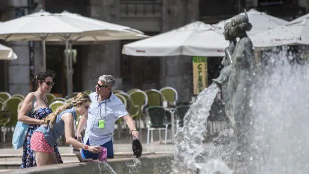 Unos turistas se refrescan en una fuente del centro de Valencia