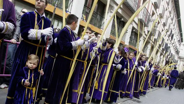 Niños y mayores esperan el paso de la burriquilla en la Procesión del Domingo de Ramos