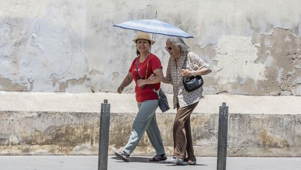 Dos mujeres se protegen del calor en una calle del centro de Valencia