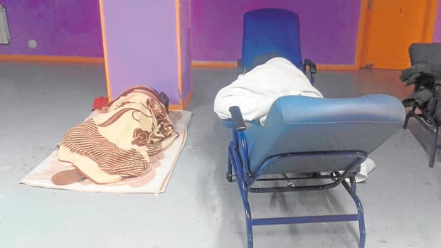 Dos personas duermen, en el suelo y un sillón, en un pasillo del centro
