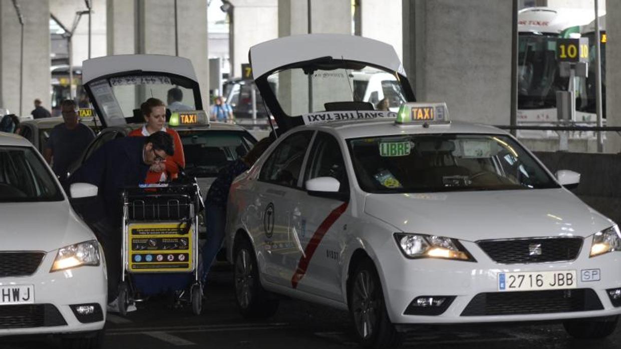 Varios taxistas ayudan a cargar las maletas a pasajeros en el aeropuerto de Madrid-Barajas