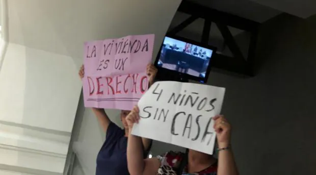 Dos protestantes muestran sus pancartas en el Pleno de Cibeles