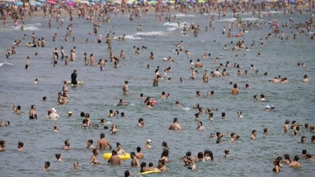 Bañistas abarrotan las aguas de la playa de la Malvarrossa, este sábado