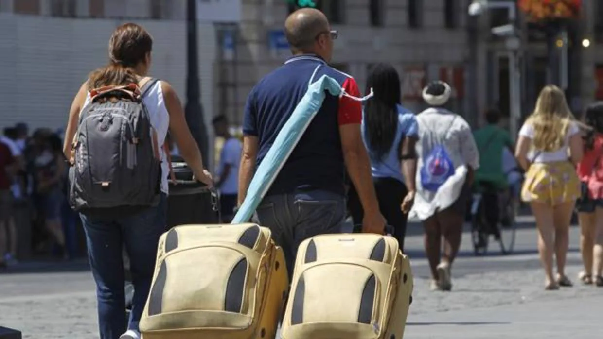 Dos turistas pasean por la capital con sus maletas