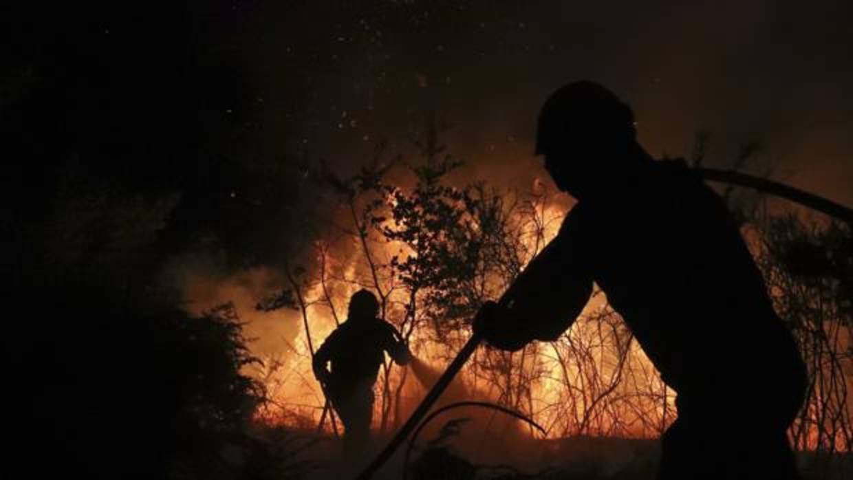 Dos brigadistas trabajan en la extinción de un fuego en Santiago esta semana