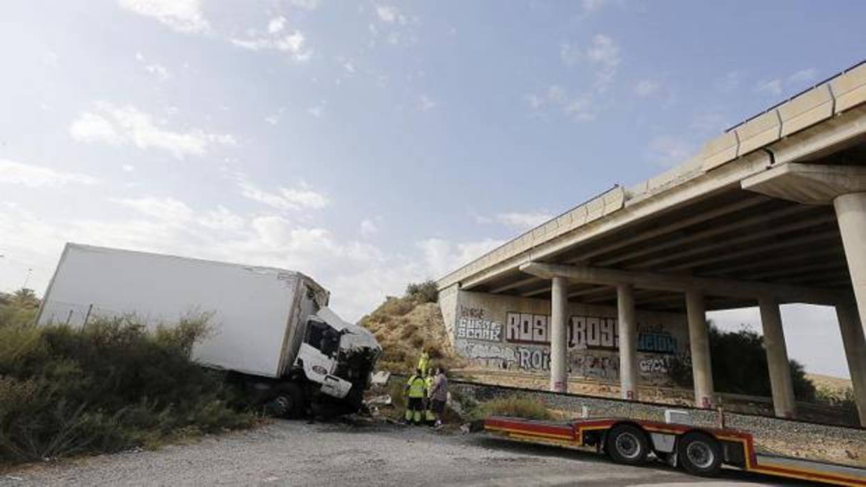 El camión junto al puente desde el que ha caído, rompiendo parte del lateral