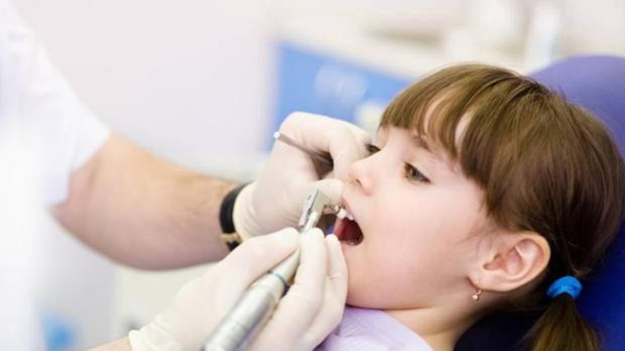 Un dentista revisa la boca a una niña, en imagen de archivo