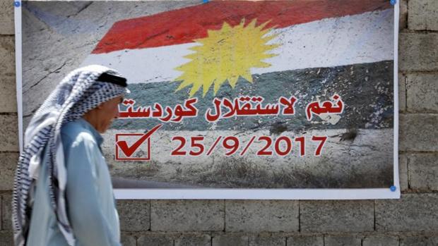 Un hombre pasa junto a un cartel a favor del referéndum, en Kirkuk, Irak