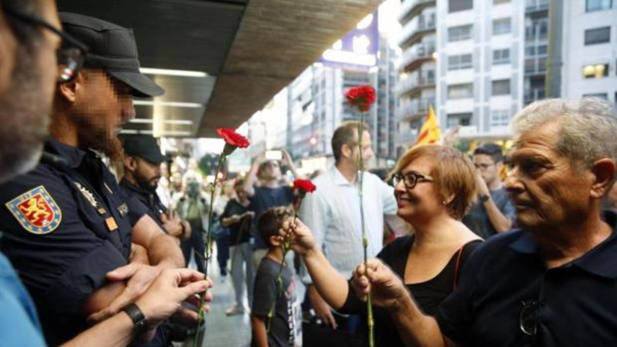 La escritora Gemma Pasqual y otros manifestantes ofrecen rosas a los agentes que custodiaban la sede de la Delegación del Gobierno en Valencia