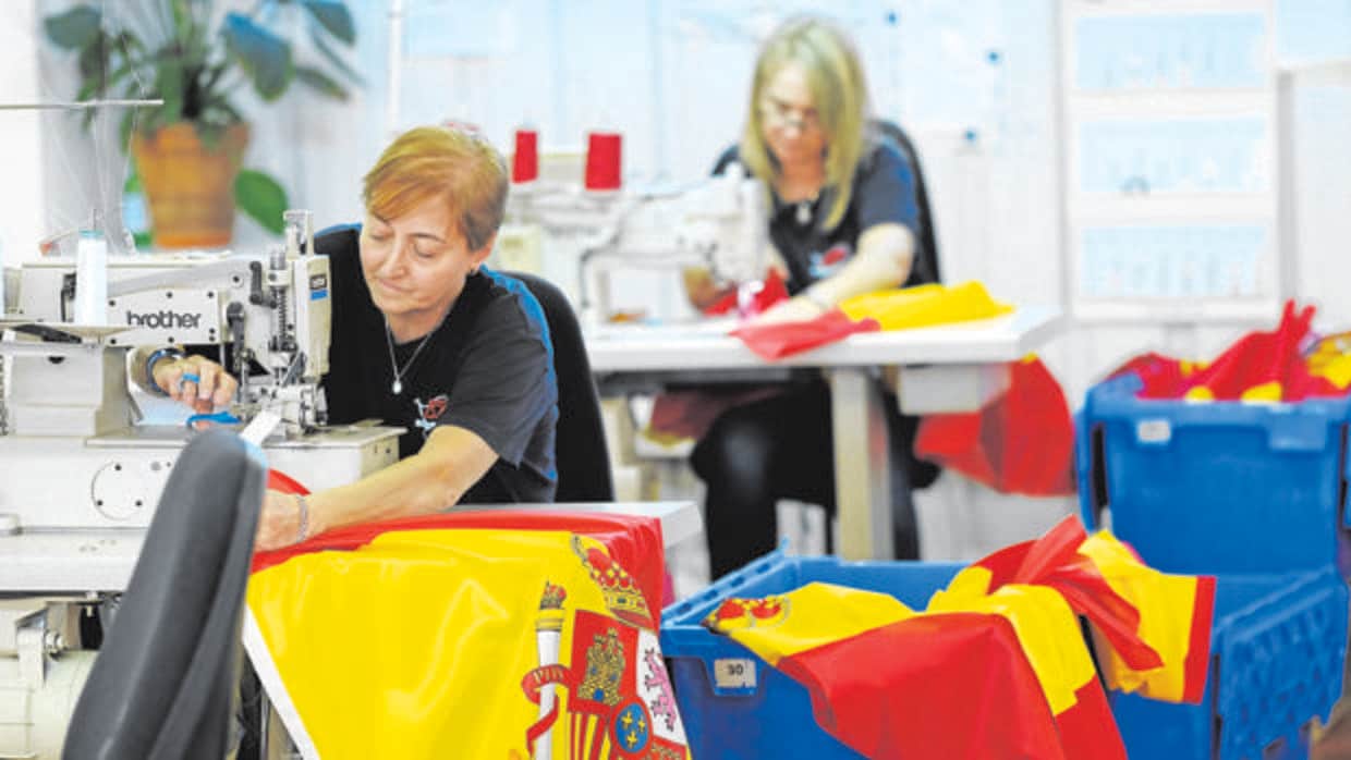 Dos trabajadoras cosen banderas en la fábrica Sosa Días