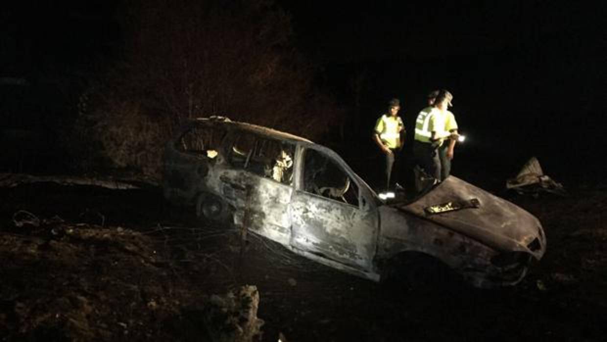 Agentes de la Guardia Civil junto al vehículo carbonizado