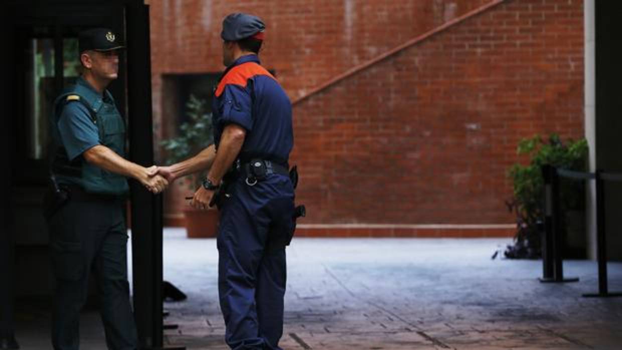 Un mosso d'esquadra saluda a un guardia civil en la entrada de la caserna de Travessera de Gracia, en Barcelona, donde permanecían arrestadas varias de las catorce personas que fueron detenidas por delitos de malversación, prevaricación y desobediencia