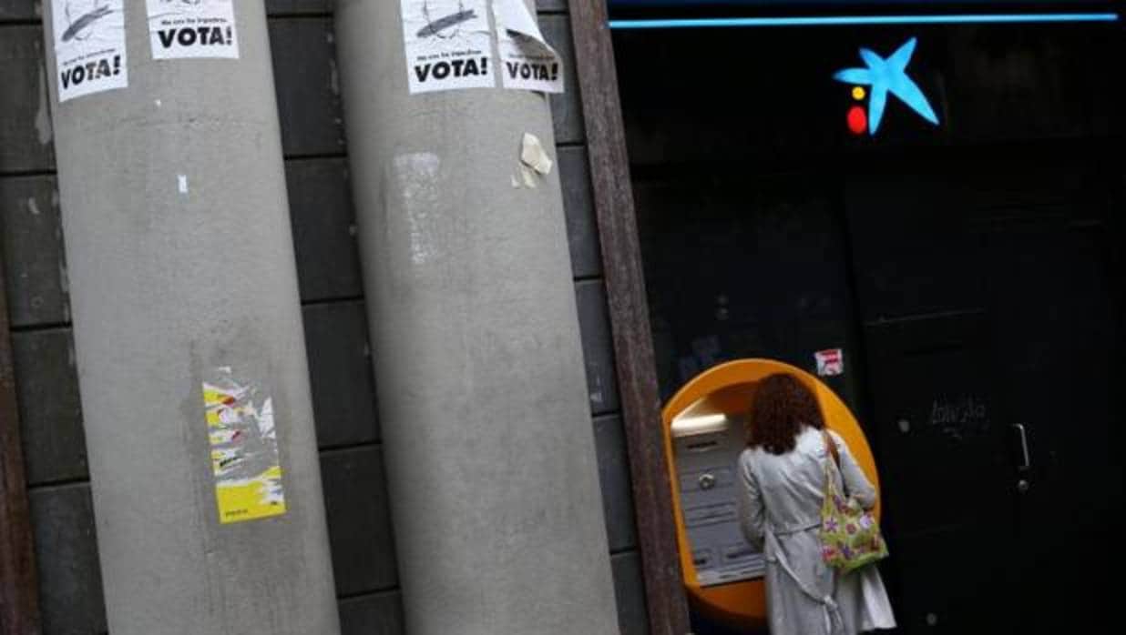 Una persona retira dinero de un cajero de CaixaBank, hoy en Barcelona