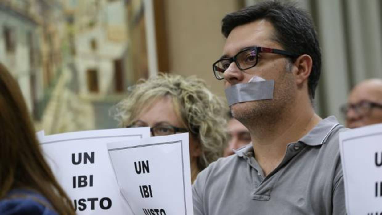 Vecinos eldenses exhiben sus carteles de protesta con la boca tapada, durante el sesión plenaria