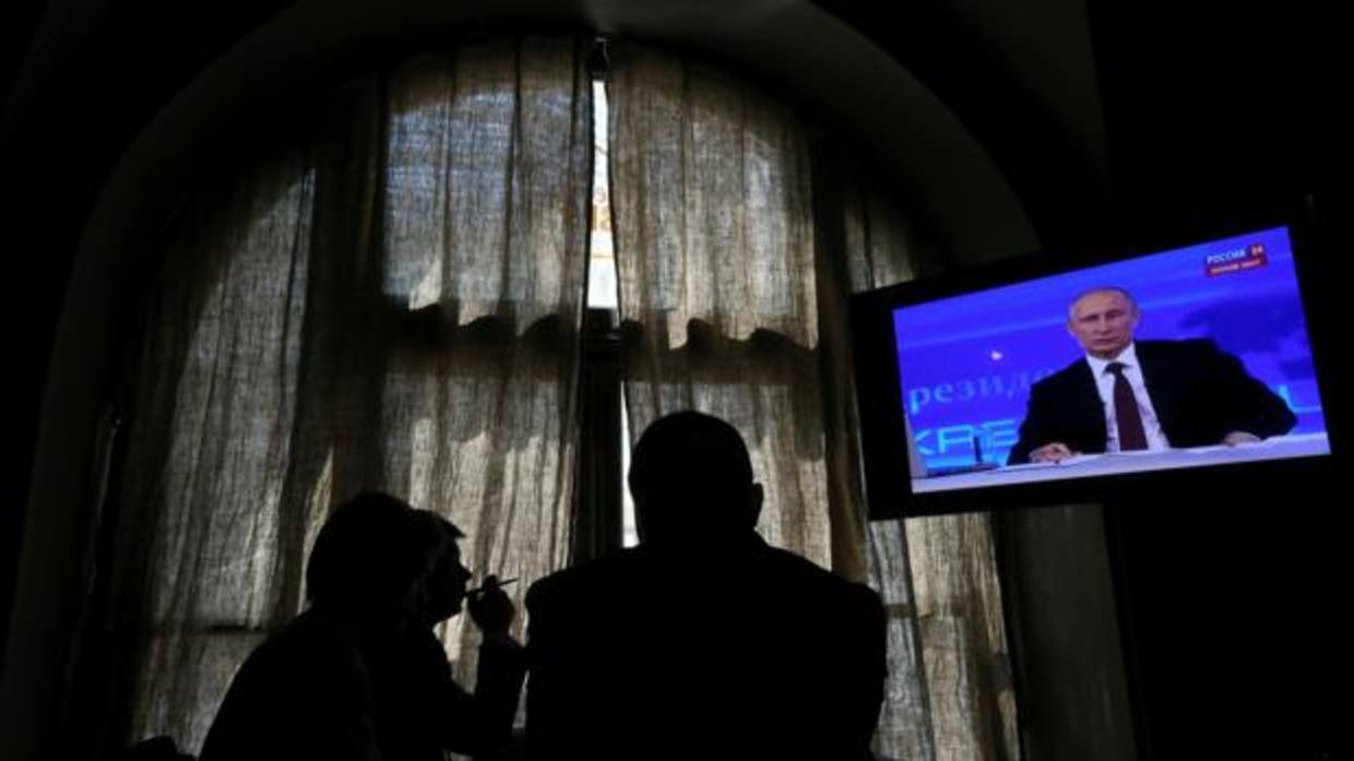 Ciudadanos rusos escuchan a Vladimir Putin en televisión