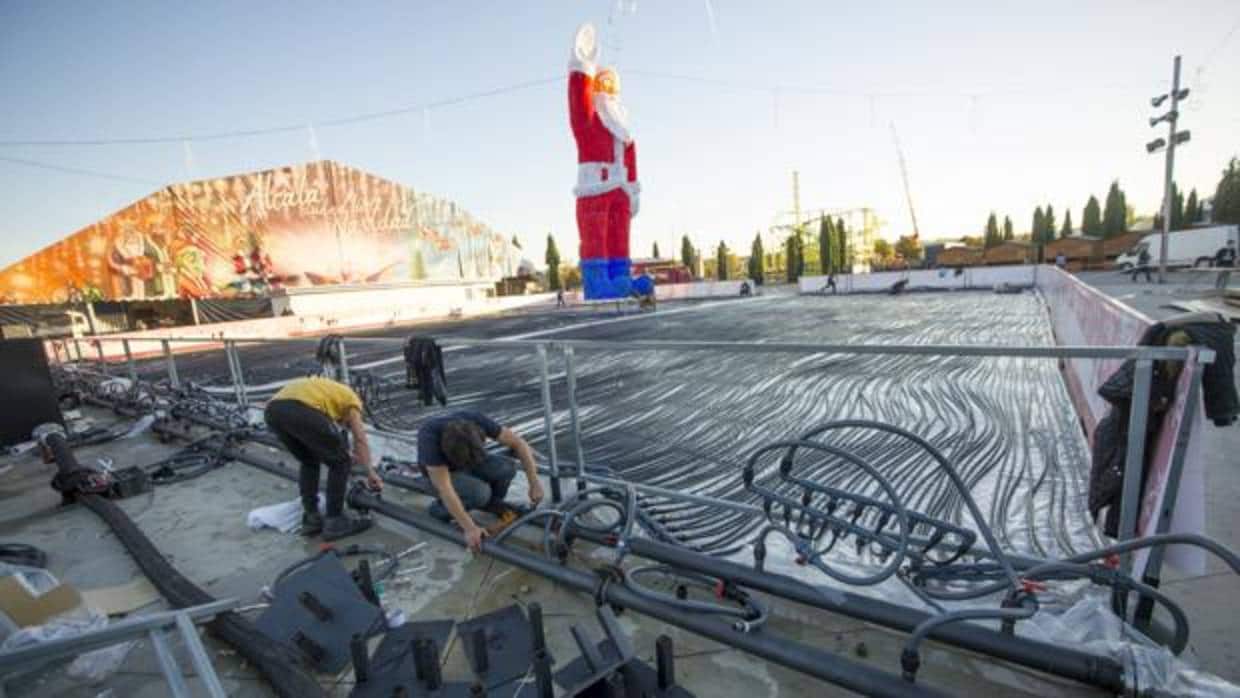 Dos operarios montan la pista de hielo en el recinto ferial de Alcalá de Henares