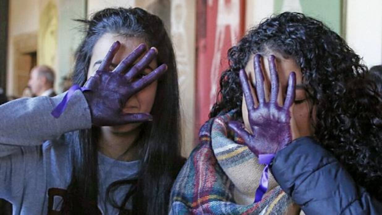 Dos jóvenes muestran sus manos teñidas de violeta en repulsa de la violencia machista