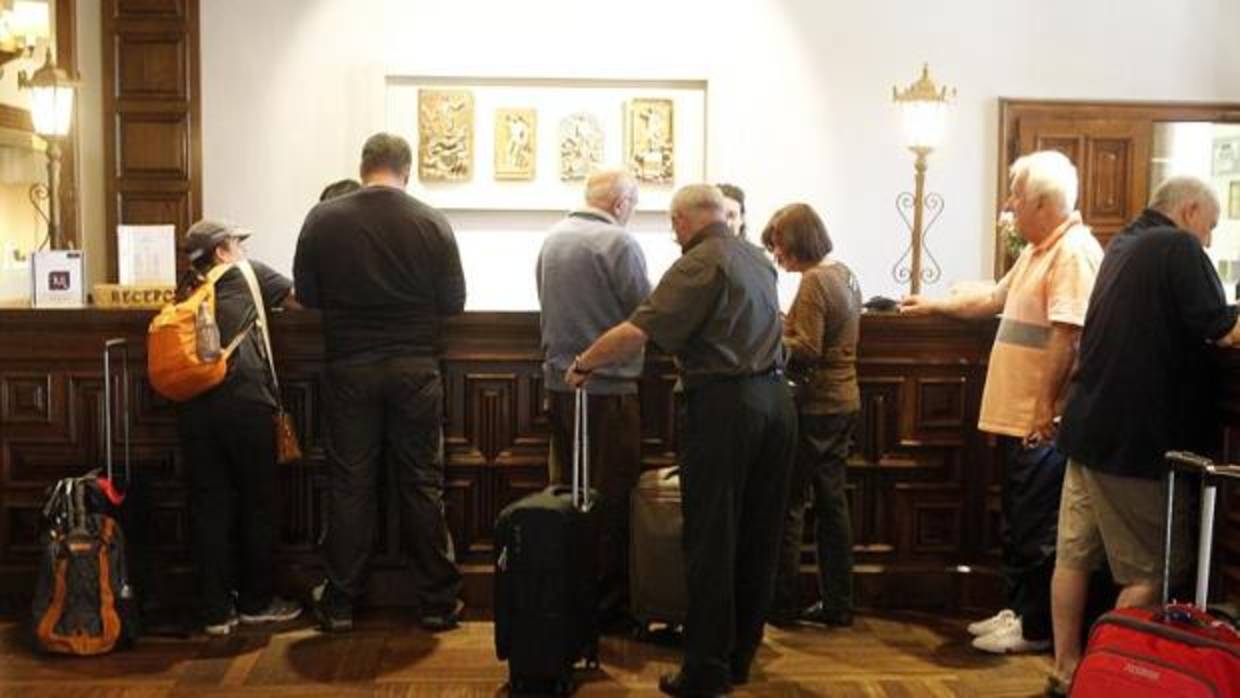 Visitantes registrándose en la recepción del Hostal de los Reyes Católicos, en Santiago de Compostela