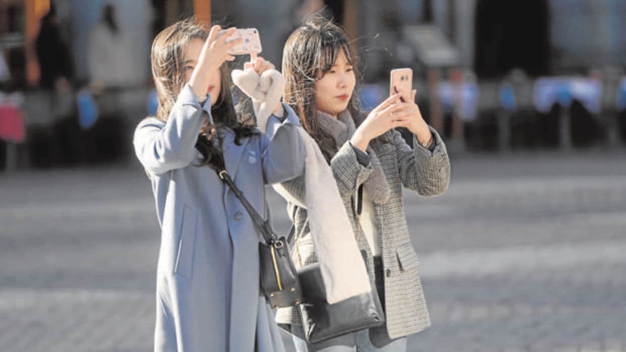 Dos turistas asiáticas toman fotografías en la Plaza Mayor
