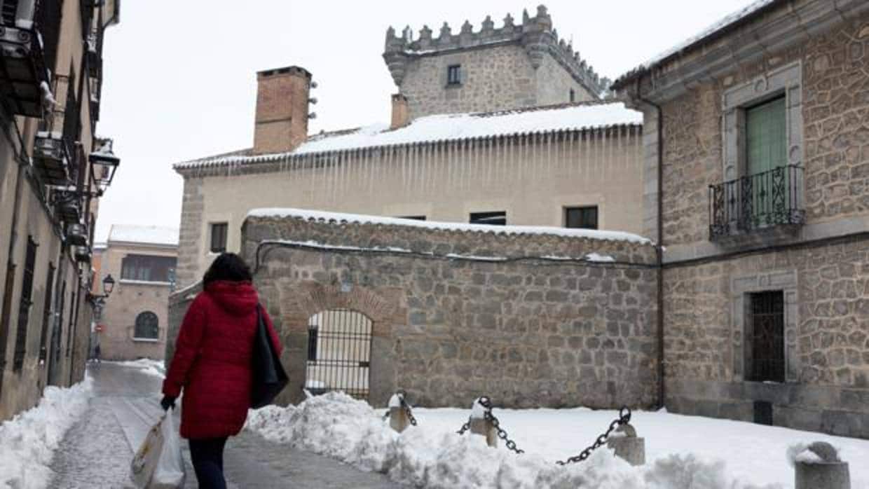Una mujer observa los carámbanos de hielo que cuelgan de la cornisa de un edificio del centro de Ávila