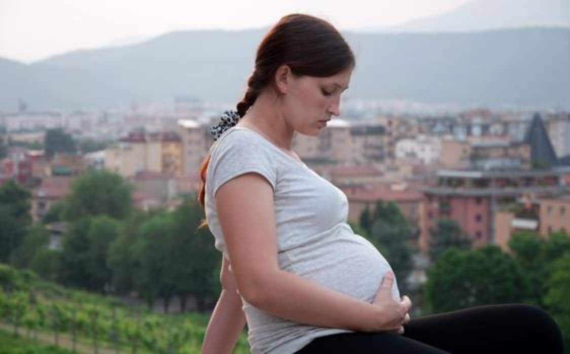 Imagen de una embarazada en un entorno urbano con polución ambiental