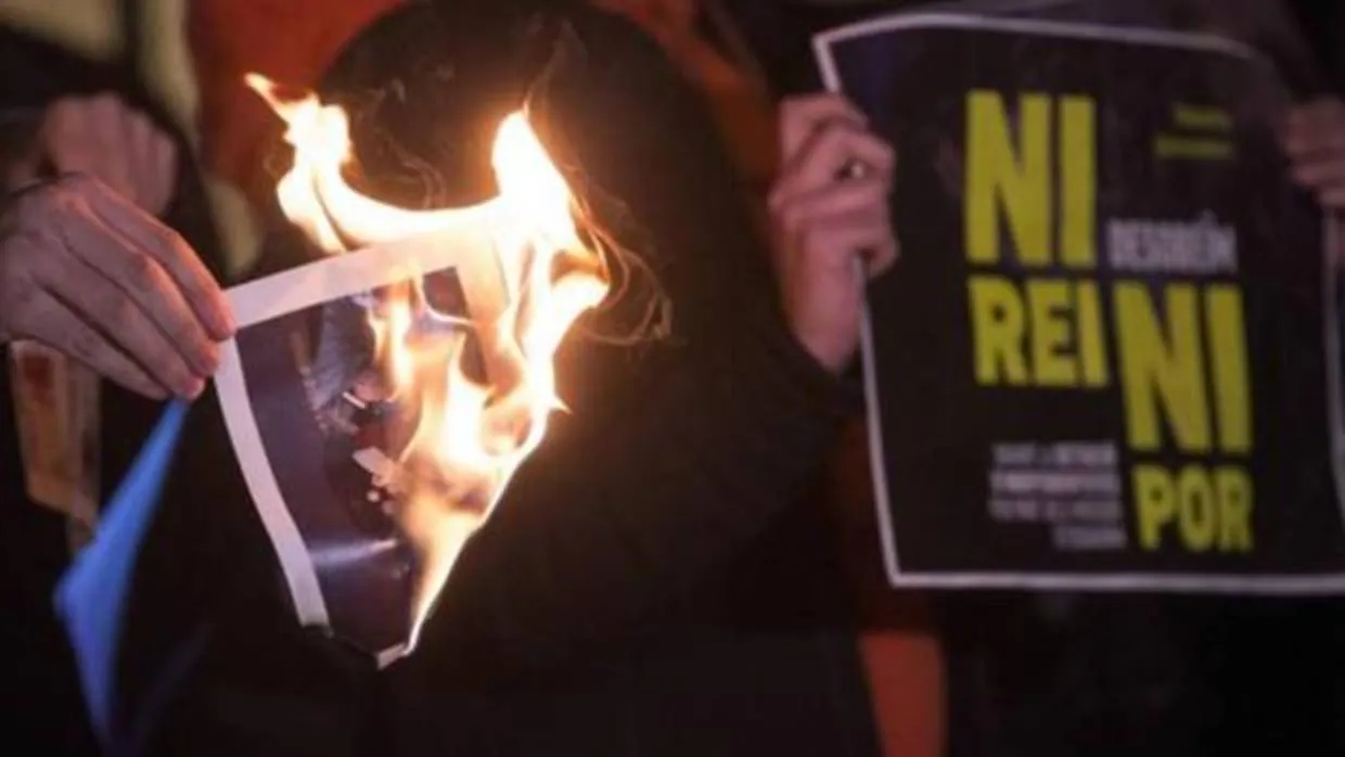 Manifestantes quemando fotos del Rey