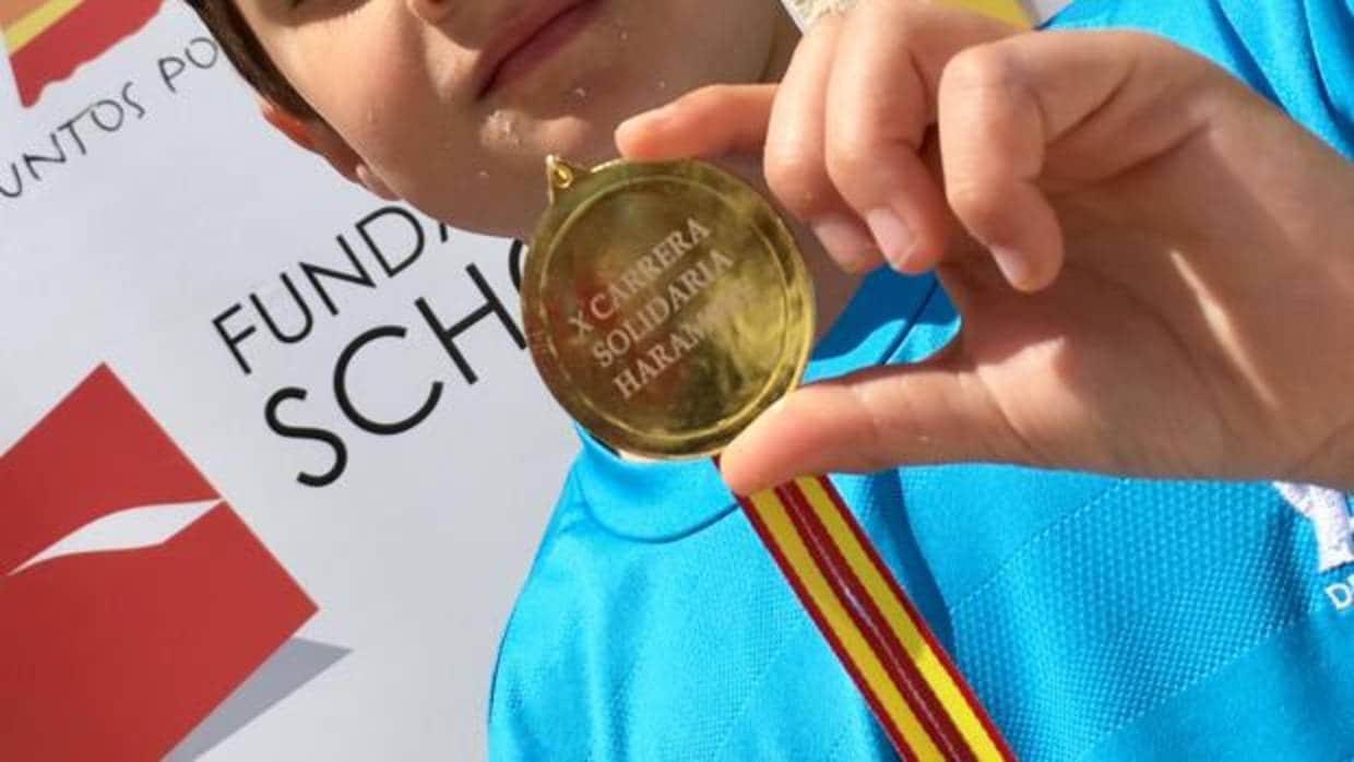 Uno de los niños participantes en la carrera con su medalla