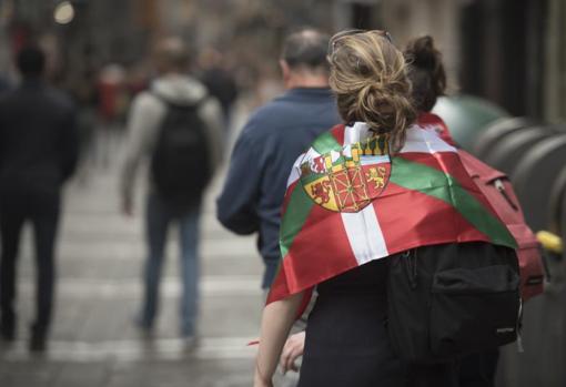 Una mujer pasea por el centro de Pamplona con una ikurriña