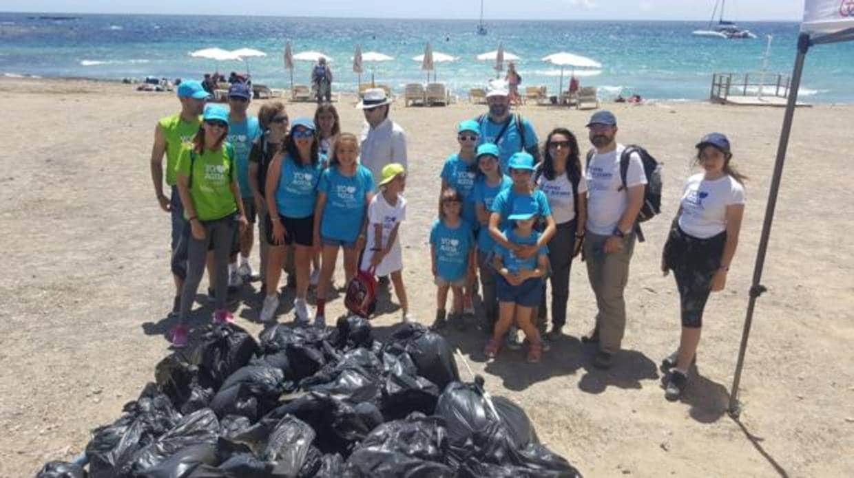 Empleados del grupo de Hidraqua junto a bolsas con residuos recogidos en una playa