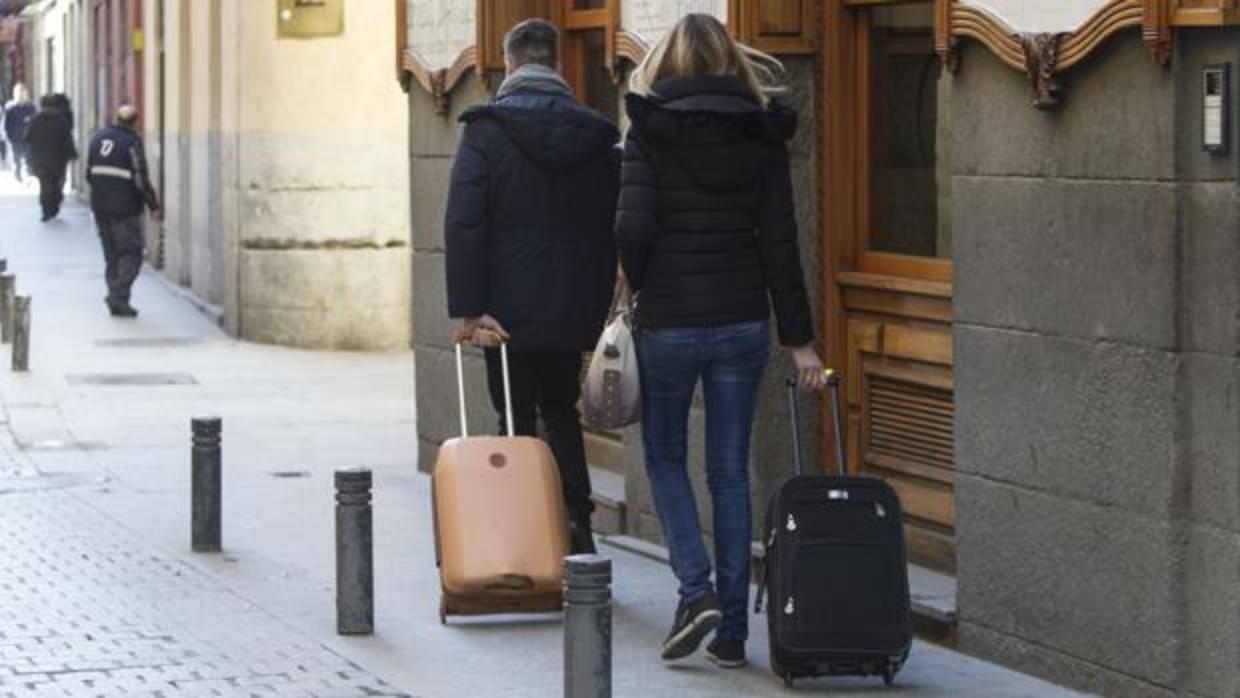 Dos turistan caminan con sus maletas por las calles del centro