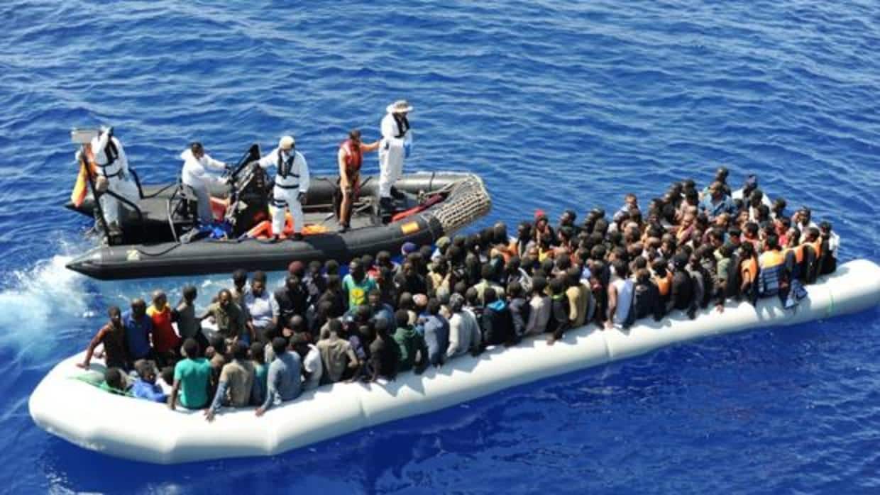 Una lancha de la fragata Reina Sofía se aproxima a una embarcación llena de inmigrantes en el Mediterráneo