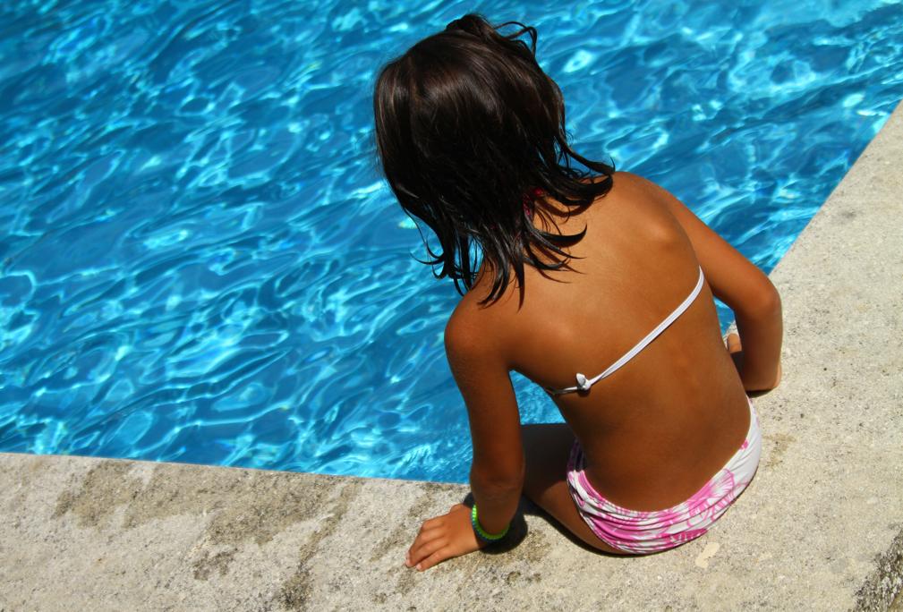 Niña sentada al borde de la piscina