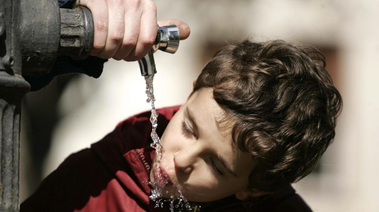 Un niño bebiendo agua en una fuente pública