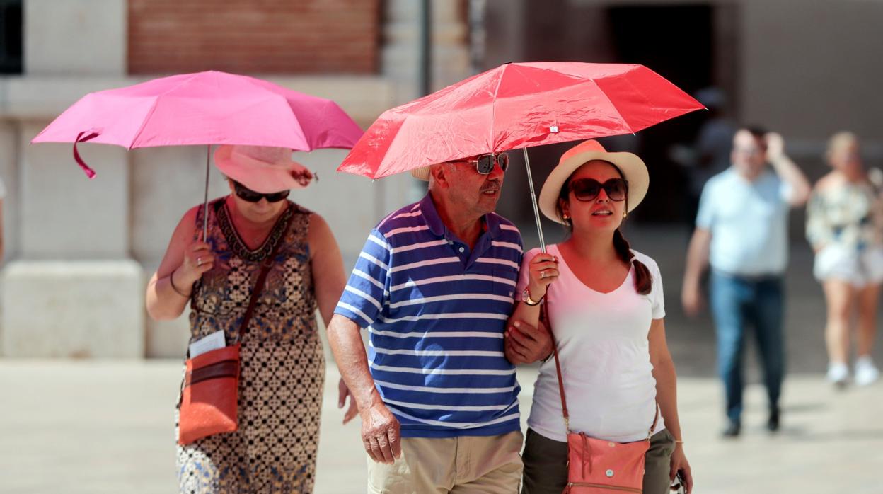 Unos turistas se protegen del calor en una imagen tomada en el centro de Valencia