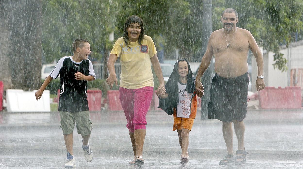 Imagen de una familia paseando bajo la tormenta cerca de la playa de La Malvarrosa de Valencia.