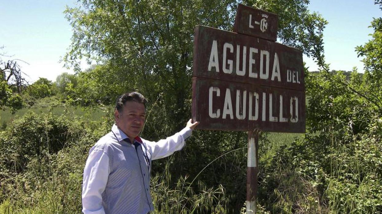 El alcalde, junto al cartel original del municipio