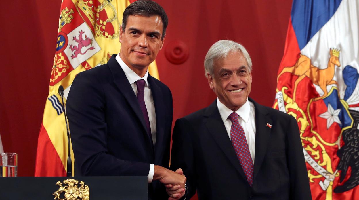 El jefe del Gobierno español, Pedro Sánchez, estrecha la mano del presidente chileno, Sebastián Piñera