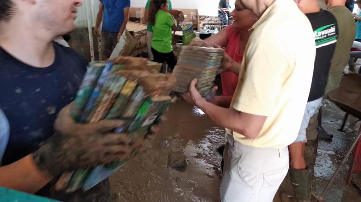 Trabajadores y vecinos recogiendo los libros llenos de barro este domingo